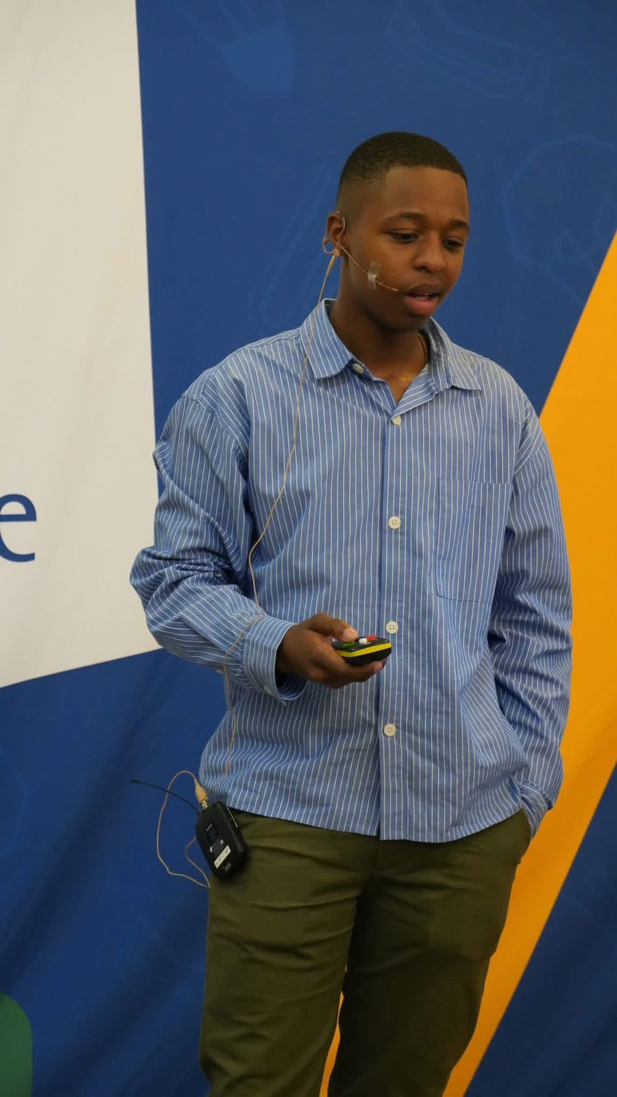 Man in a blue striped shirt holding a smartphone against a colorful background